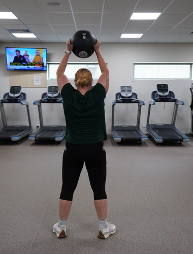 person holds medicine ball above head