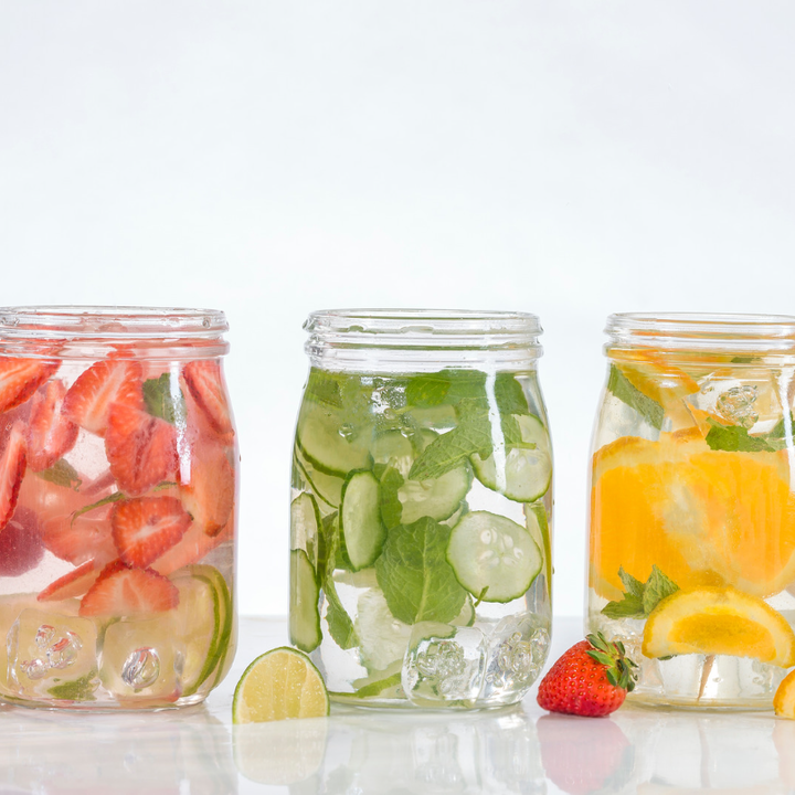 three jars of water flavoured with strawberries, cucumber and oranges in order