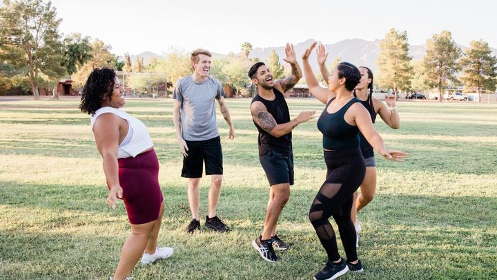 Group of friends laugh and high five on sports field