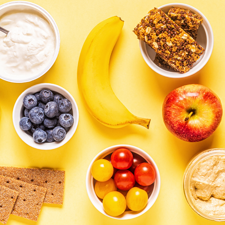 selection of healthy snacks including fresh and dried fruits, hummus and yoghurt.