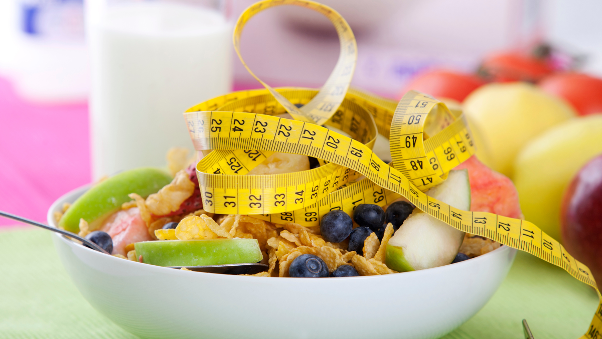 Bowl of cereal with fruit with a tape measure sitting on top